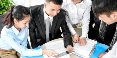 Business professionals working round a desk with a tablet and papers