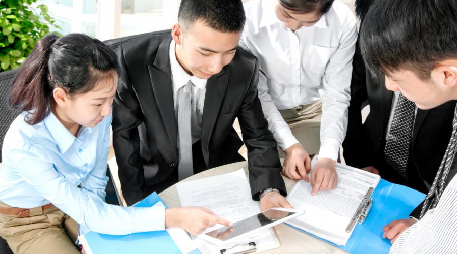 Business professionals working round a desk with a tablet and papers